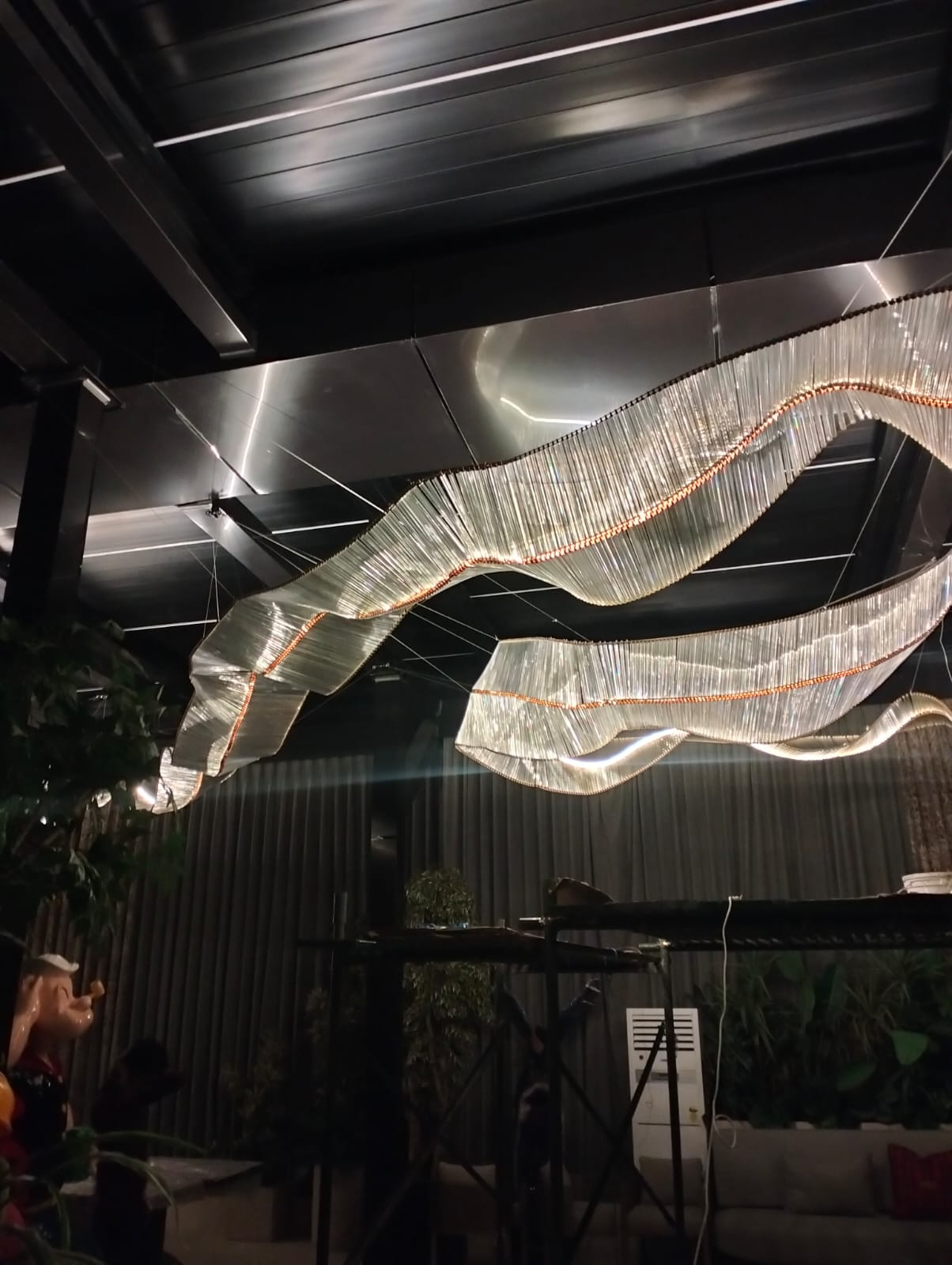 Modern ribbon-style chandelier installed in a luxury hotel and banquet hall with double-height ceilings.